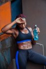 Donna etnica atletica che beve acqua — Foto stock