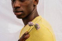 Recadré mâle afro-américain méconnaissable avec bouquet de fleurs sauvages regardant la caméra sur fond blanc — Photo de stock