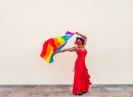 Elegante donna afroamericana in abiti e occhiali alla moda con bandiera colorata guardando altrove durante la celebrazione — Foto stock