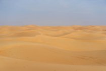 Paisaje desértico minimalista con dunas de arena y cielo azul claro en Emiratos - foto de stock