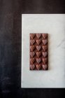 Вид зверху смачні шоколадні цукерки з горіхами у формі серця на мармуровому лотку на фоні столу — стокове фото