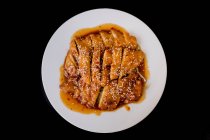 Vista superiore di pollo piccante saporito preparato su piatto bianco su tavolo scuro in ristorante asiatico — Foto stock