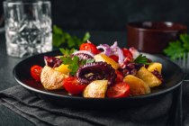 Leckerer Salat mit Oktopus und verschiedenen Gemüsen und Kräutern auf dem Teller — Stockfoto