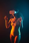 Mulher étnica anônima explorando realidade virtual em fone de ouvido em fundo preto — Fotografia de Stock