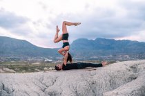 Вид збоку жінки, що балансує догори ногами чоловіка під час сеансу акройоги в горах — стокове фото