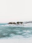 Рябь моря у снежного горного хребта на фоне облачного неба зимой на Лофских островах, Норвегия — стоковое фото