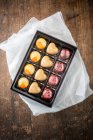 Vue du dessus de bonbons au chocolat colorés sucrés en boîte placée sur une table en bois — Photo de stock