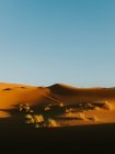 Cielo azul nublado sobre árido desierto con dunas arenosas en día soleado cerca de Marrakech, Marruecos - foto de stock
