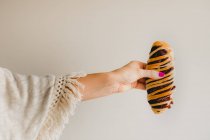 Mãos de mulher com manicure rosa brilhante segurando saboroso pão azuki cozido no fundo cinza — Fotografia de Stock