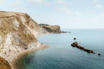 From above idyllic seascape with rocks called Durdle Door and people relaxing on seashore on summer day — Stock Photo