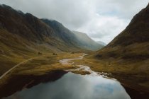 Cielo coperto sulle colline che riflettono in lago con acqua calma nella campagna del Regno Unito — Foto stock