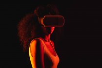 Анонімні етнічні жінки, що вивчають віртуальну реальність у гарнітурі на чорному тлі — стокове фото