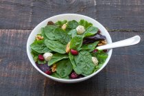 High angle of delicious salad with spinach and beans and walnuts served in bowl on wooden table for healthy lunch — Stock Photo