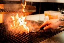 Cultivo anónimo chef masculino asando sabrosa empanada mientras se preparan hamburguesas en cocina del restaurante - foto de stock