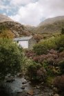 Casa blanca situada cerca del pequeño arroyo del río en el día nublado en la naturaleza del Reino Unido - foto de stock