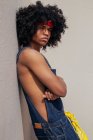 Junger ethnischer Mann in Retro-Kleidung mit Afro-Frisur lehnt an der Wand und schaut weg — Stockfoto