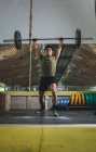 Focalizzato asiatico atleta maschio facendo stacco con pesante bilanciere durante l'allenamento in palestra guardando altrove — Foto stock