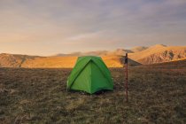 Tente de camping verte placée sur une colline herbeuse dans les hautes terres au coucher du soleil au Pays de Galles — Photo de stock