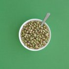 Vue du dessus des fèves surgelées dans un bol servi sur une table verte — Photo de stock