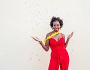 Mulher afro-americana excitada com os braços estendidos e boca aberta de pé sob queda confete no evento contra fundo branco — Fotografia de Stock