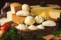 Збірка італійського сиру на столі з свіжими овочами і хвилястим петрушкою з базильним листям на спатулах. — стокове фото