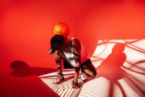 Donna nera con abito da basket in studio utilizzando gel di colore e luci del proiettore su sfondo arancione — Foto stock