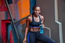 Sportliche ethnische Frau trinkt Wasser — Stockfoto
