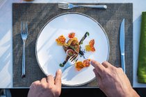 Mani che tengono posate su piatto di fegato d'oca fritto ben guarnito al ristorante di alta cucina all'aperto — Foto stock