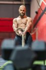 Знизу сильний спортсмен тягне мотузку з важкими вагами під час інтенсивних тренувань у сучасному спортзалі — стокове фото