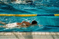 Вид сбоку паралимпийского спортсмена в очках и кепке без стиля ручного плавания в бассейне между дорожками — стоковое фото