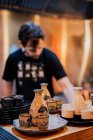 Молодой человек в фартуке готовит азиатские блюда, стоя за стойкой в рамен-баре — стоковое фото