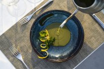 Garçom derramando sopa de lentilha no restaurante de alta cozinha ao ar livre — Fotografia de Stock