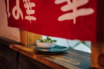 Traditional Asian dish in white ceramic bowl on wooden window in restaurant — Stock Photo