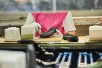 Detalhe do trabalhador aplicando cola para a sola de sapatos em uma linha de produção de fábrica de sapatos chineses — Fotografia de Stock