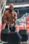 Von unten starker Sportler beim Seilziehen mit schweren Gewichten beim intensiven Training im modernen Fitnessstudio — Stockfoto