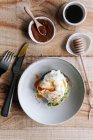 Appetitoso fetta di pane di grano con avocado e uovo in camicia in cima posto sul piatto sul tavolo di legno — Foto stock