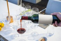 Serveur versant du vin rouge dans un verre au restaurant de haute cuisine en plein air — Photo de stock