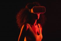 Mulher étnica anônima explorando realidade virtual em fone de ouvido em fundo preto — Fotografia de Stock