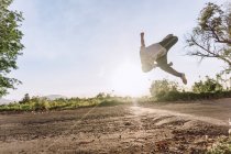 Acrobático macho pulando acima do solo e realizando truque de parkour perigoso no dia ensolarado — Fotografia de Stock