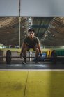 Focused Asian male athlete doing deadlift with heavy barbell during workout in gym looking away — Stock Photo