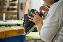 Detalhe das mãos da mulher ao verificar os sapatos na linha de produção de controle de qualidade na fábrica de sapatos chineses — Fotografia de Stock