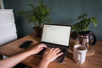 De cima, corte freelancer feminino irreconhecível digitando no laptop enquanto está sentado à mesa durante o trabalho remoto — Fotografia de Stock