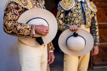Crop unrecognizable bullfighters in traditional costume decorated with embroidery holding hats and preparing for corrida festival — Stock Photo