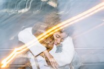 Fröhliche junge Afroamerikaner geben Huckepack-Fahrt zu glücklichen Freundin mit lockigem Haar in trendigen Outfit in der Nähe von Freeze Lights — Stockfoto