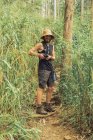 Весёлый путешествующий фотограф фотографирует на фотокамеру во время летних приключений в лесу — стоковое фото