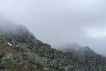 Paisaje tranquilo con cordillera cubierta de niebla contra el cielo nublado de la mañana en el Parque Nacional Guadarrama en Madrid, España - foto de stock