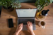 Visão superior da colheita freelancer feminino irreconhecível digitando no laptop enquanto sentado à mesa durante o trabalho remoto — Fotografia de Stock