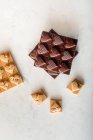 Vista superior de deliciosos caramelos de chocolate con nueces en forma de corazón esparcidos sobre fondo blanco - foto de stock