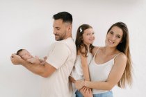 Delighted couple with naked infant and cute little girl standing on white background — Stock Photo