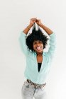 Juguetón joven afroamericano hembra en traje de moda divertirse tocando el pelo afro sobre fondo blanco - foto de stock